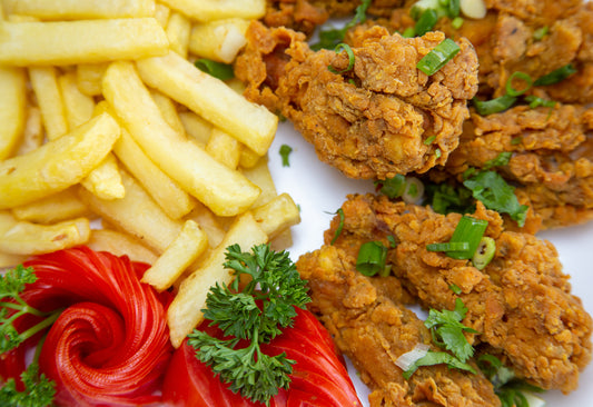 Crispy fried chicken pieces with french fries and tomato garnish