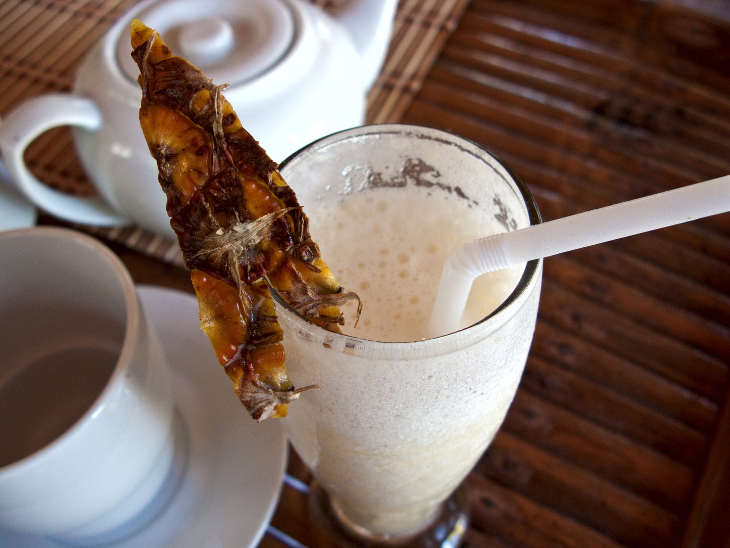 Tall glass of fruit milkshake with pineapple garnish