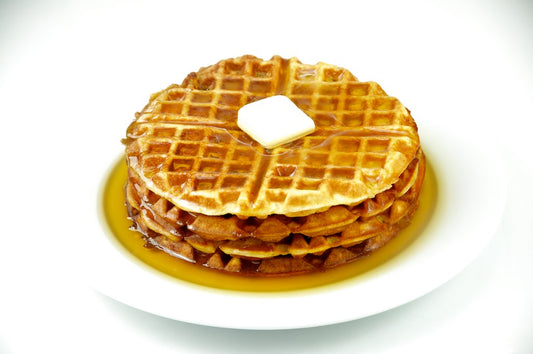 Stack of round waffles with maple syrup and butter